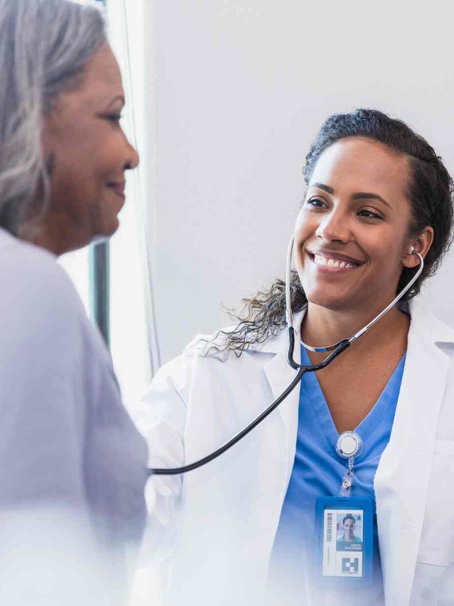 Medica mujer sonriente revisa a paciente mujer adulta mayor con estetoscopio. Antecedentes de telemedicina